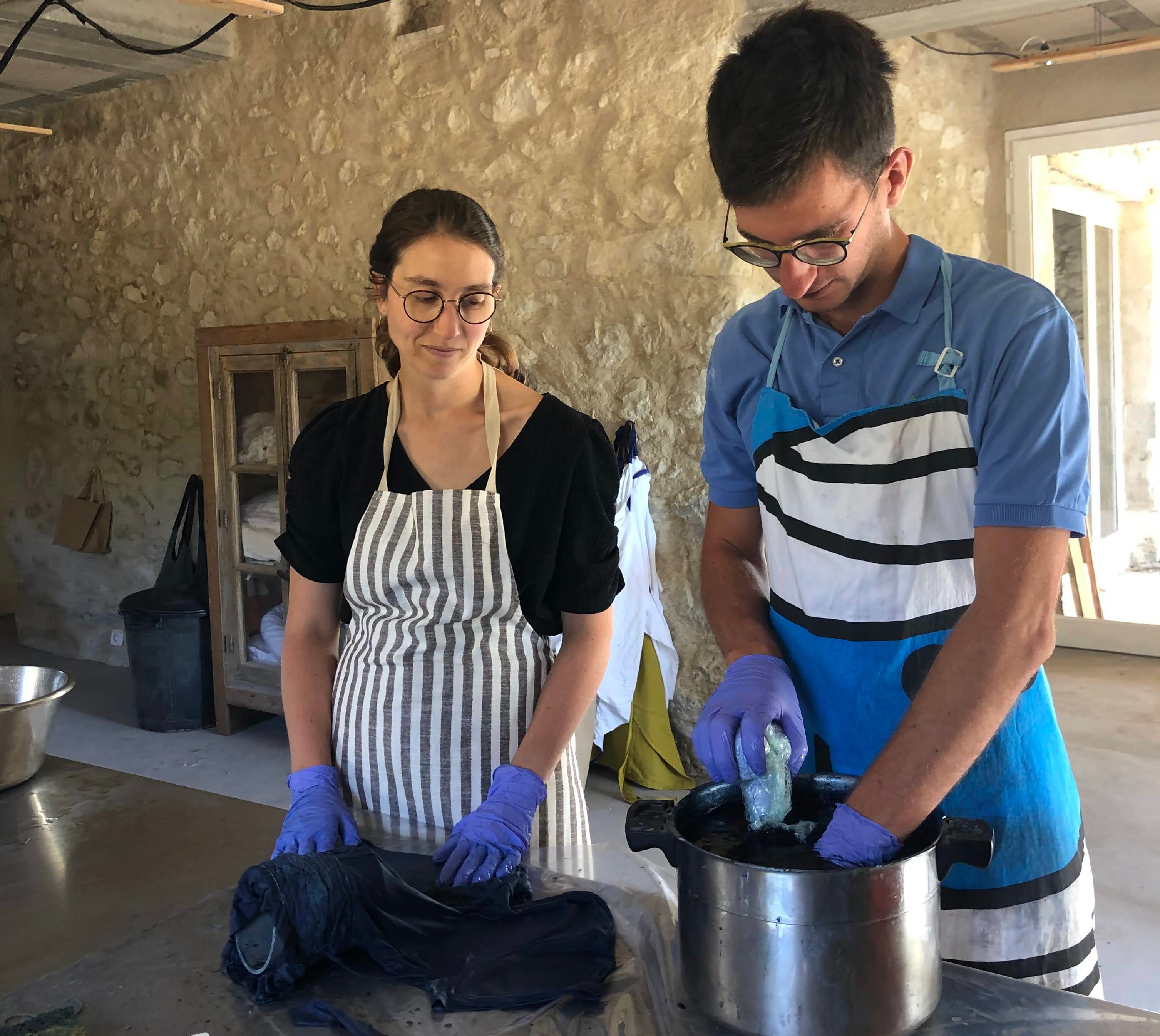 Participants plongeant des tissus dans un bain d'indigo lors d'un stage à l'Atelier Ilys