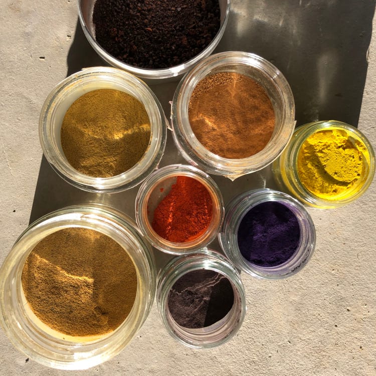 Pots de pigments naturels de différentes couleurs — ocre, indigo, vert, rouge — préparés à l'Atelier Ilys